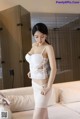 A woman in a white lingerie standing on a bed.