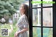 A woman standing in front of a window looking out the window.