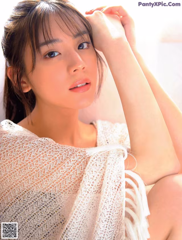 A woman in a white dress sitting on a bed.
