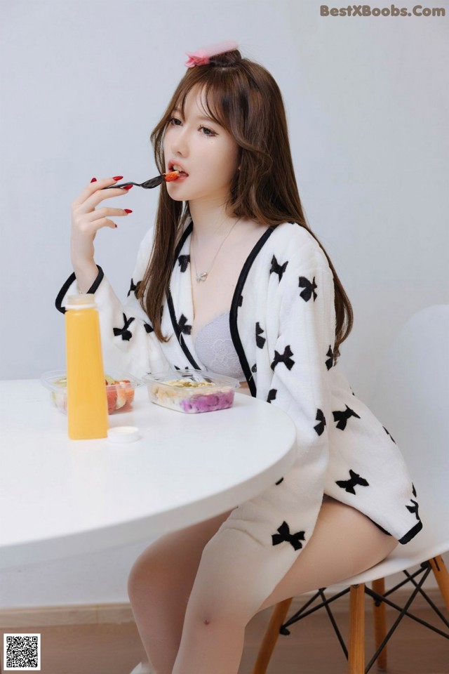 A woman sitting at a table eating a piece of food.