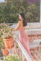 A woman in a pink dress standing on a balcony.