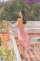 A woman in a pink dress standing on a balcony.