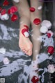 A woman's feet in a bathtub filled with rose petals.