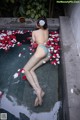 A woman laying in a bathtub filled with rose petals.