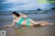 A woman in a green bikini laying on the beach.